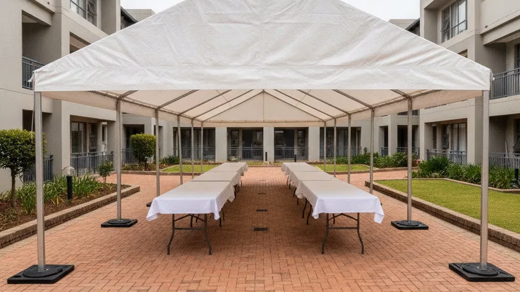Aluminium frame tent standing on weight plates on brick paving in a Durban complex courtyard
